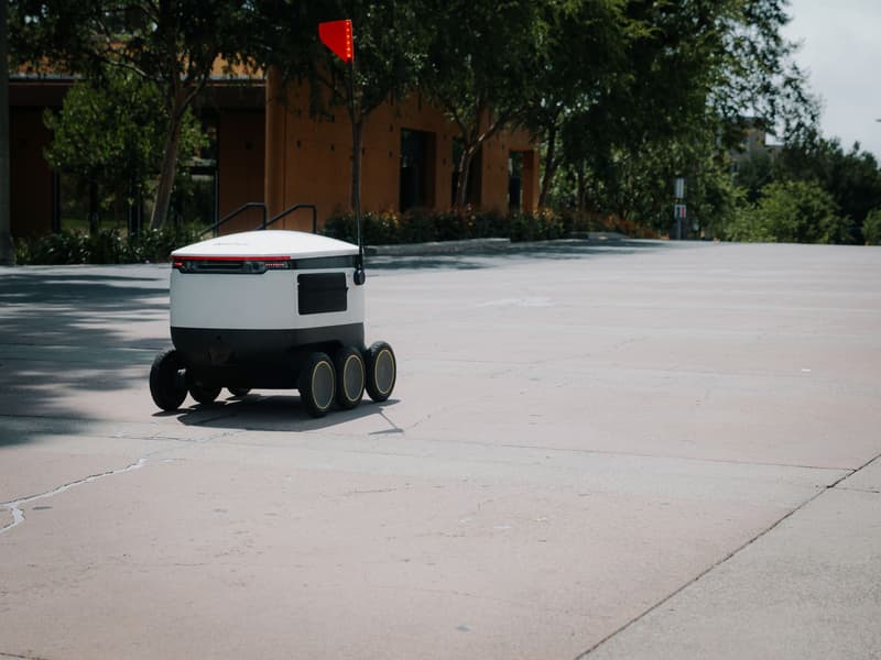 Un robot di consegna autonomo a sei ruote che percorre un marciapiede urbano