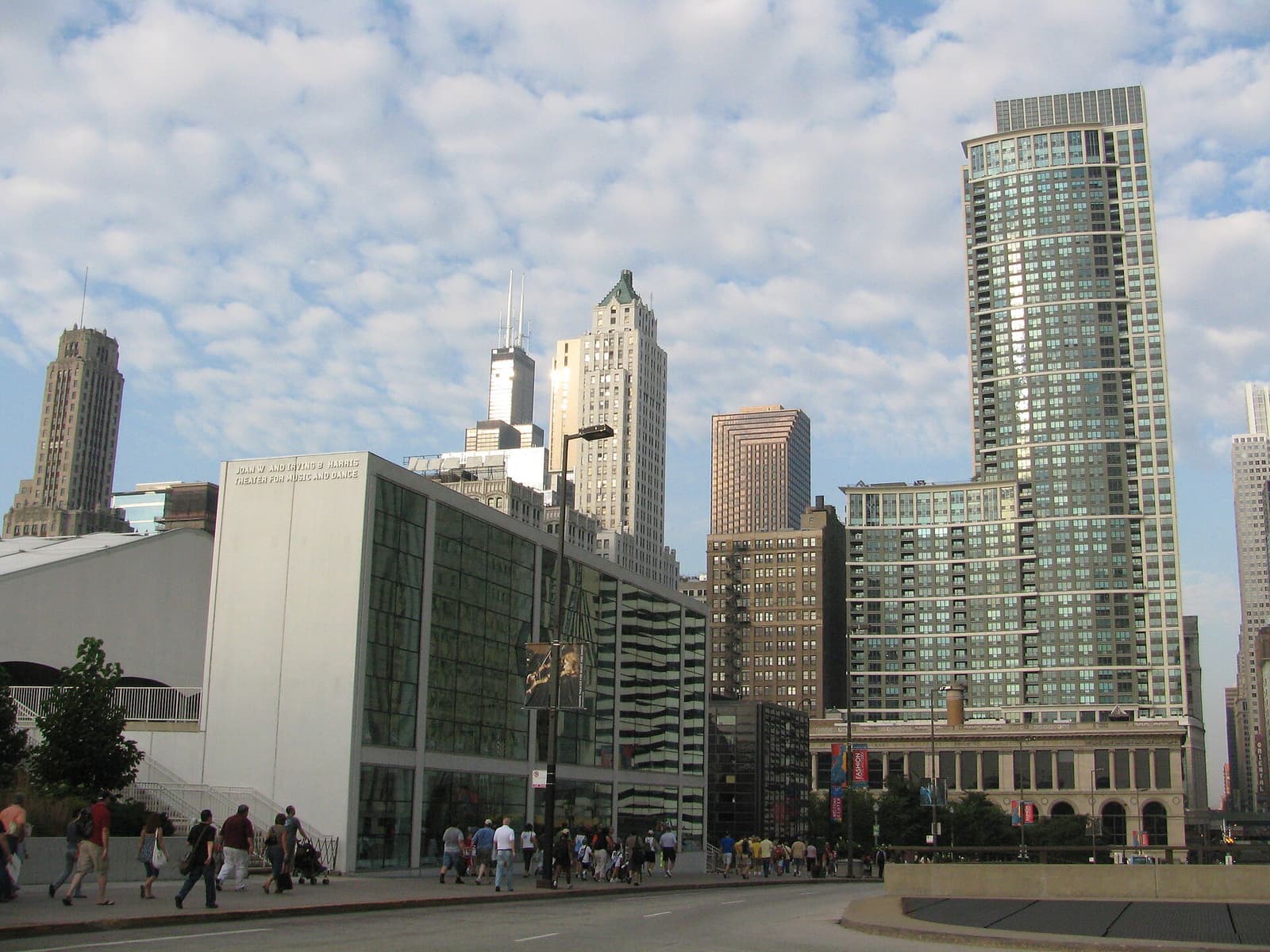 De witte glazen gevel van het Harris Theater aan Randolph Street, met torens erachter
