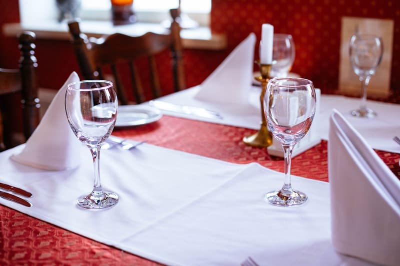 Mit Kerzenlicht gedeckter Restauranttisch mit Weingläsern und weißen Servietten in London