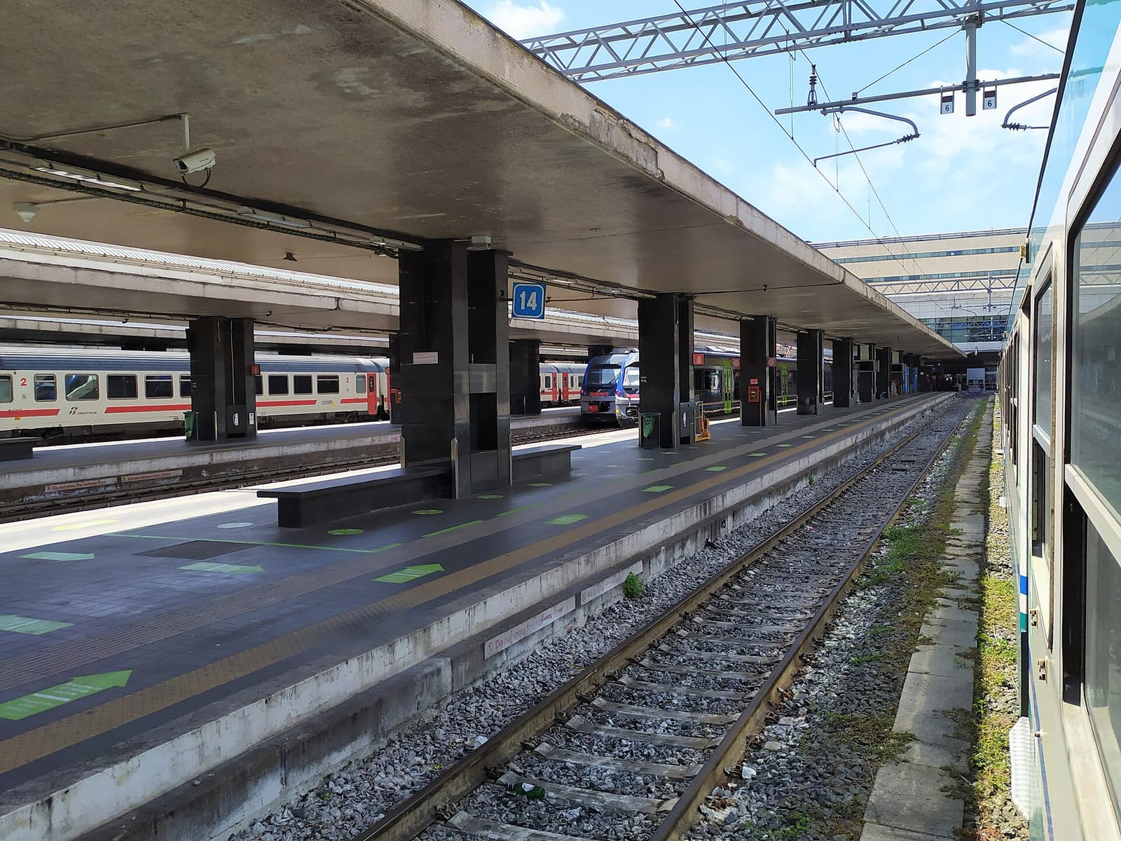 Empty platform under the canopy at Roma Termini station, with trains stopped on both sides