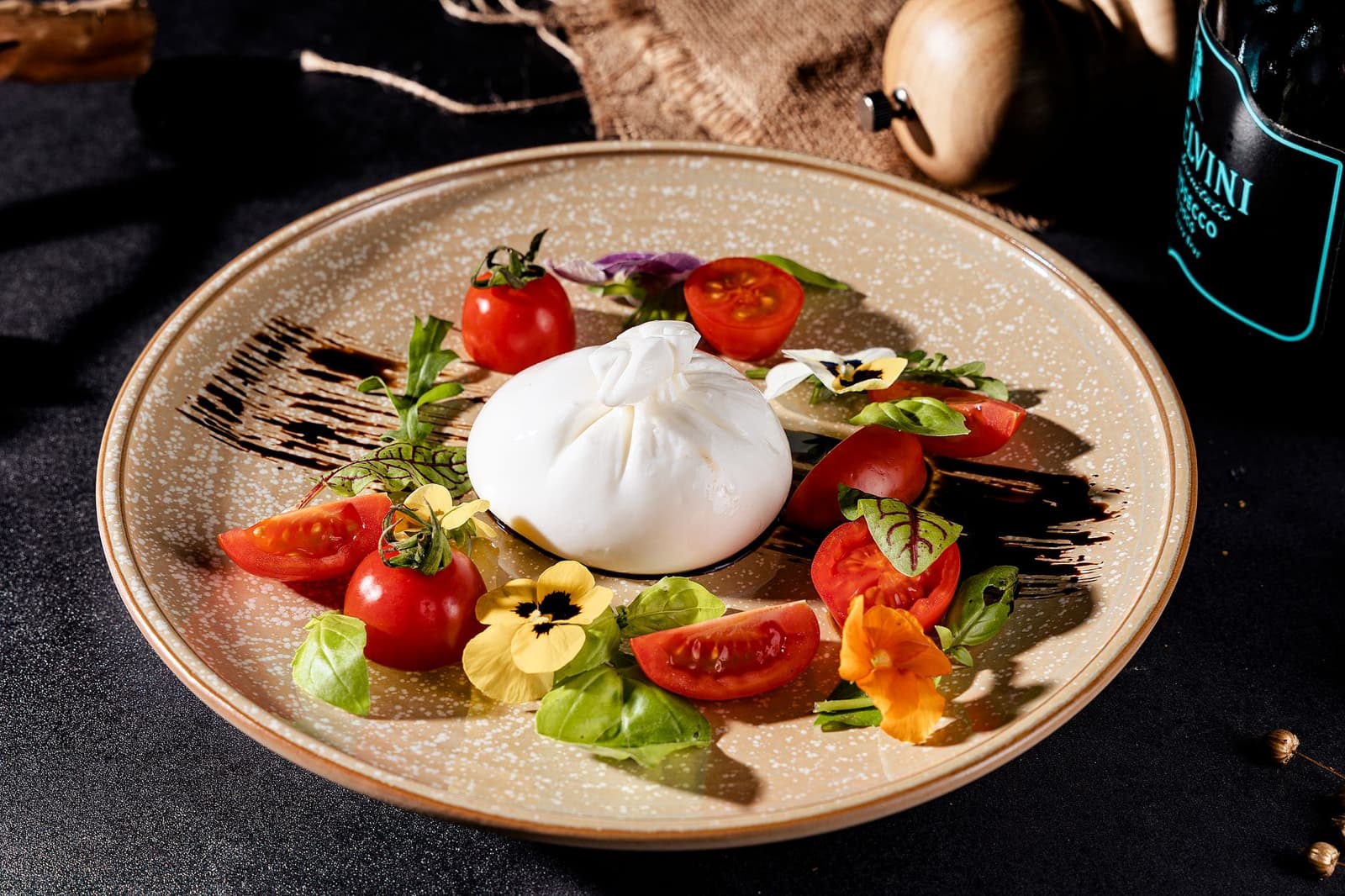Burrata avec tomates cerises, basilic et fleurs comestibles sur une assiette