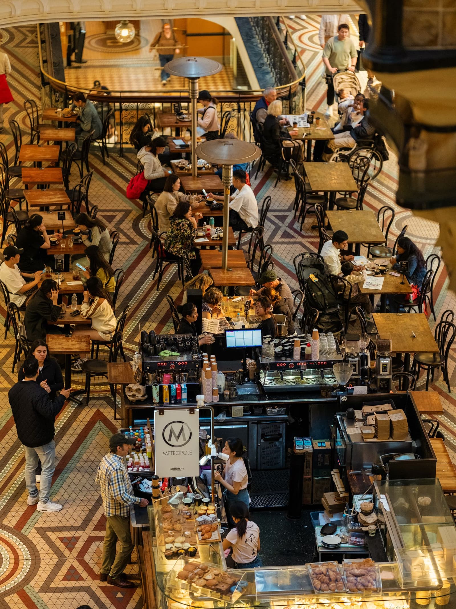 Blick von oben auf einen belebten Cafe-Gastraum mit Gaesten an Holztischen