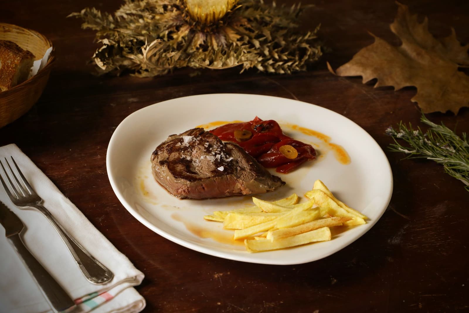 Grilled steak with roasted peppers and fries on a white plate