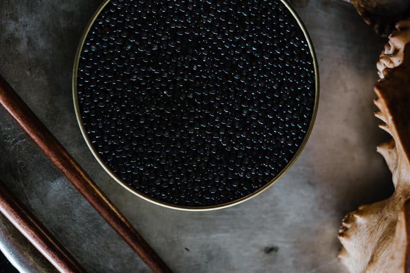 Une boîte ronde de caviar noir vue de dessus sur une table sombre