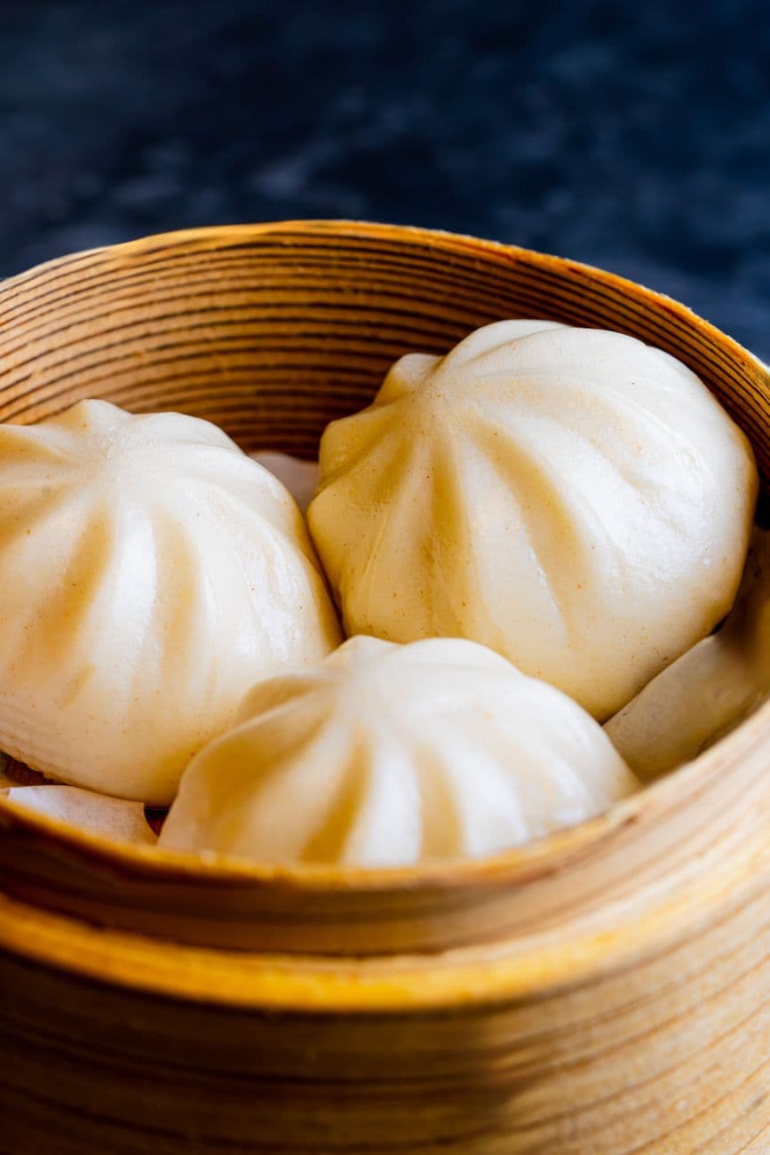 Trois char siu bao vapeur dans un panier en bambou