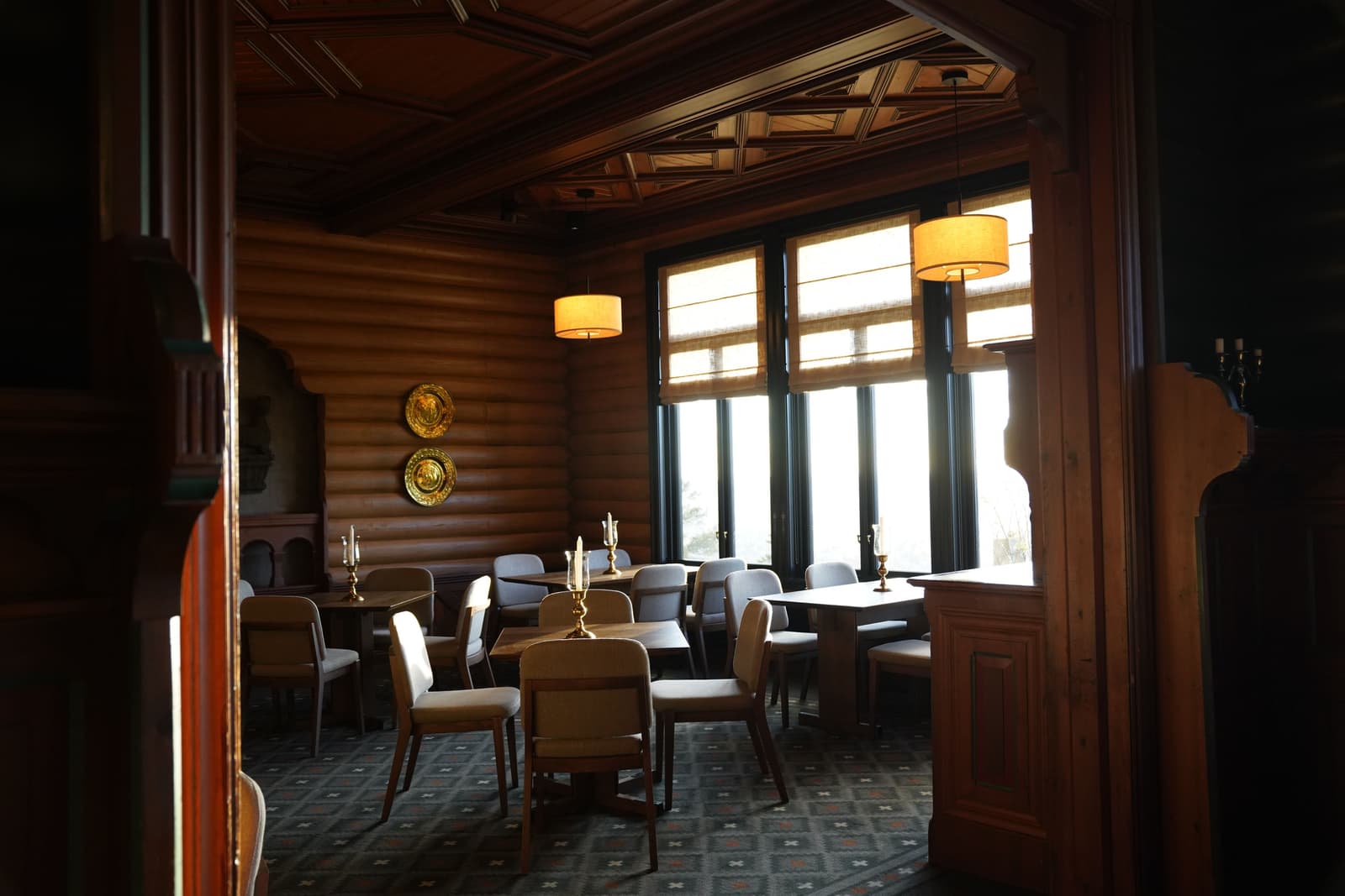 A warmly lit, wood-panelled pub dining room with candlelit tables set for service