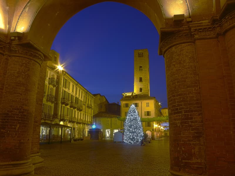Die Piazza Risorgimento in Alba in der Dämmerung, durch den Bogen der Domvorhalle gesehen