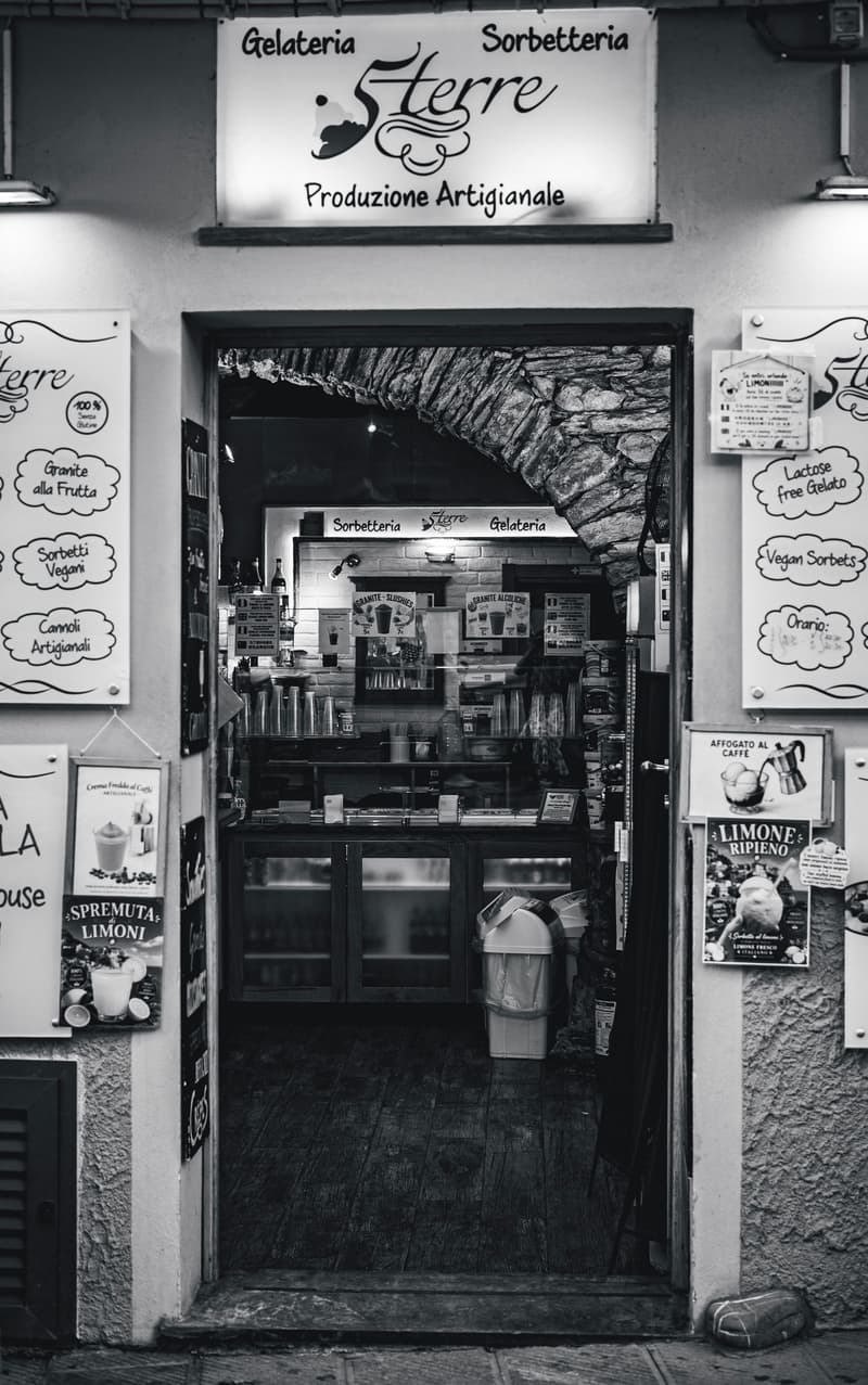 Black and white photo of a charming gelateria shopfront with handwritten menu boards