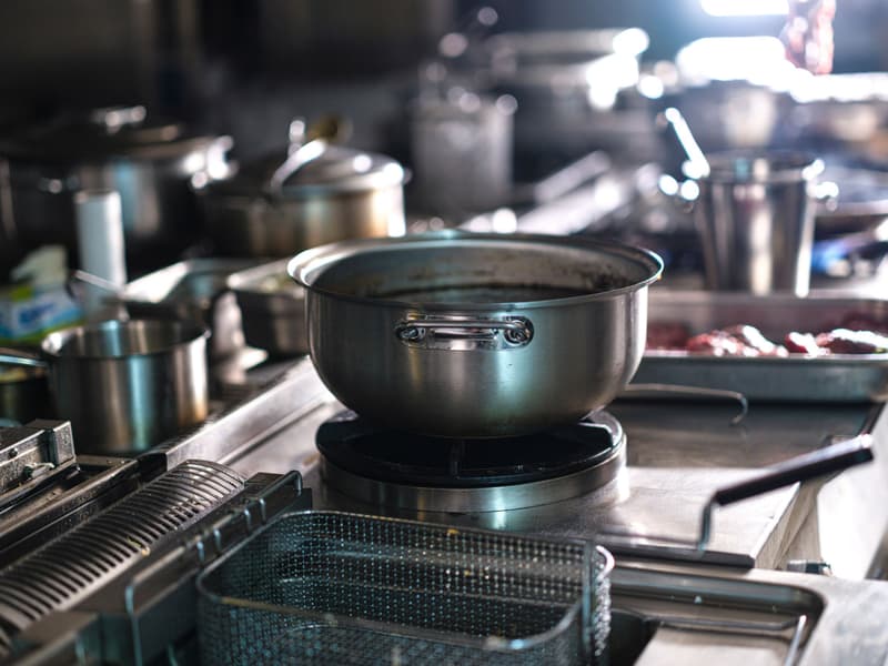 Olla grande de acero sobre un fogón de gas en una cocina profesional en uso