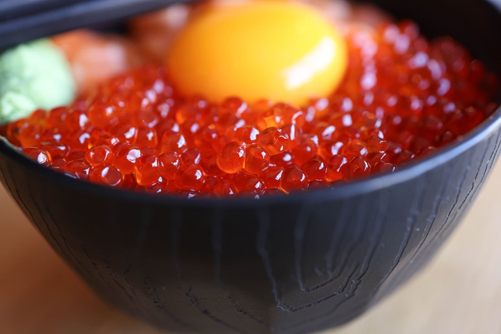 Cuenco de brillante hueva de salmón ikura con yema cruda y wasabi