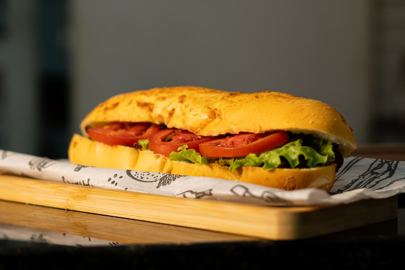 Nahaufnahme eines frischen Sub-Sandwiches mit Salat und Tomate auf einem Holzbrett