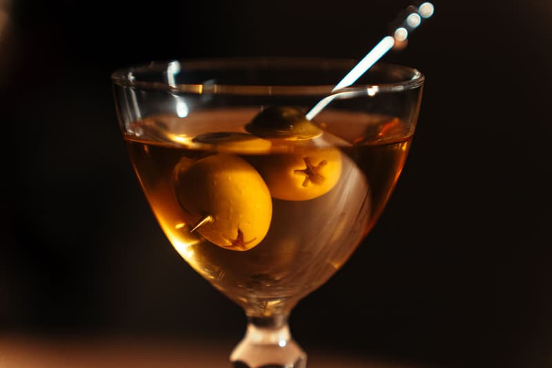 Un martini clásico con dos aceitunas en un palillo en un bar de hotel en penumbra
