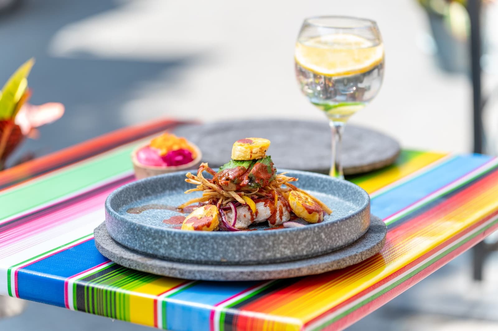 Poisson grillé avec banane plantain frite et sauce à l'avocat sur une table rayée en terrasse
