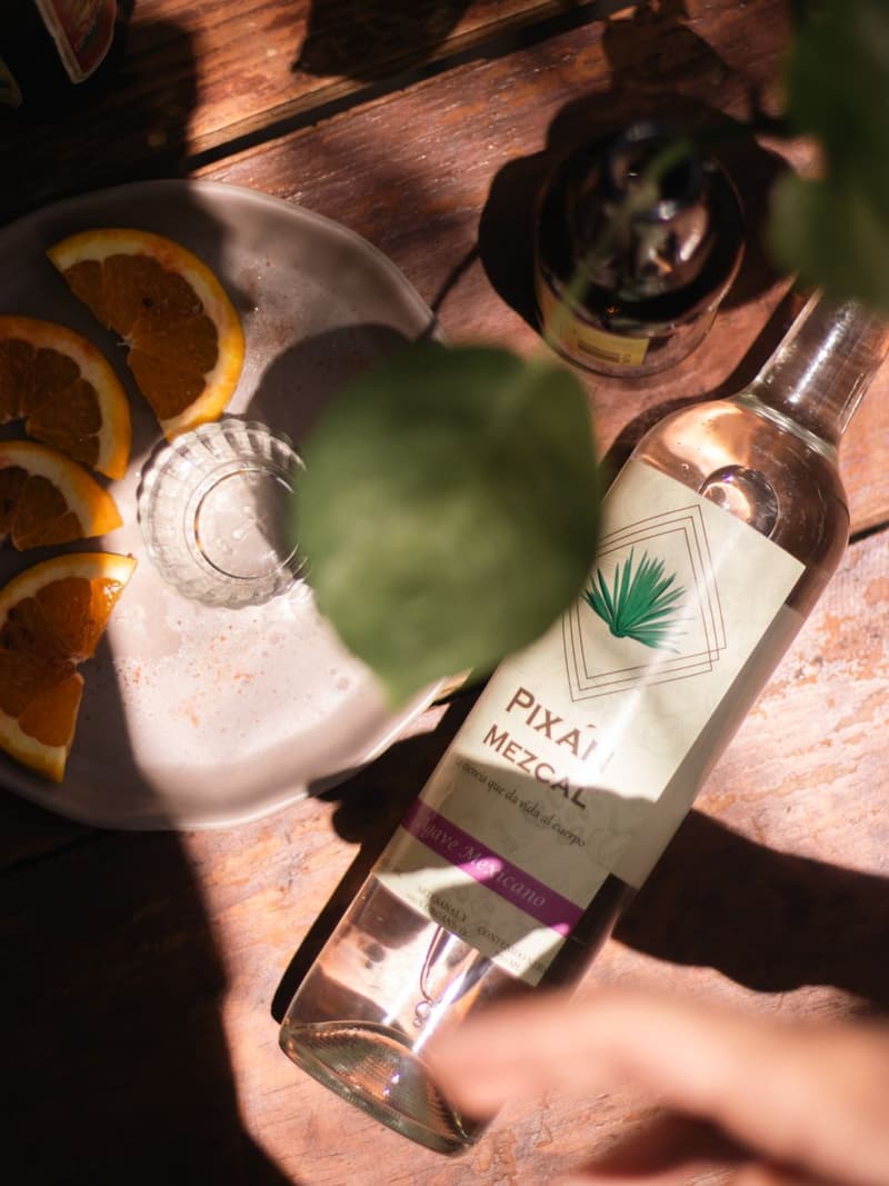 Présentation artistique de mezcal avec des oranges tranchées sur un comptoir