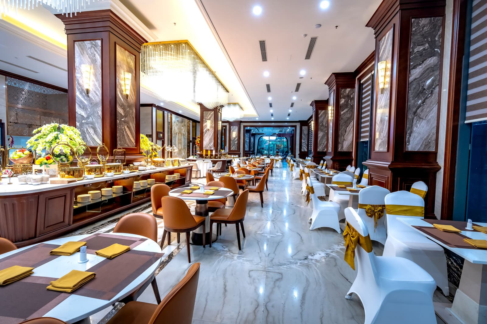 Un'elegante sala da pranzo di ristorante d'hotel con pavimenti in marmo, lampadari e tavoli apparecchiati