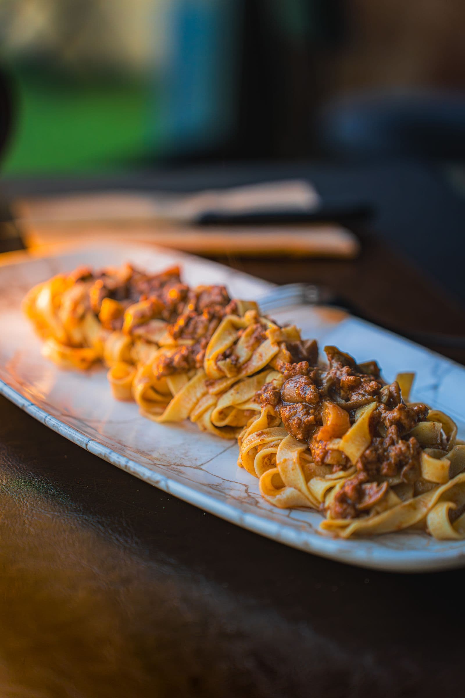 Pappardelle fraiches melangees a un riche ragu de sanglier sur un plat blanc
