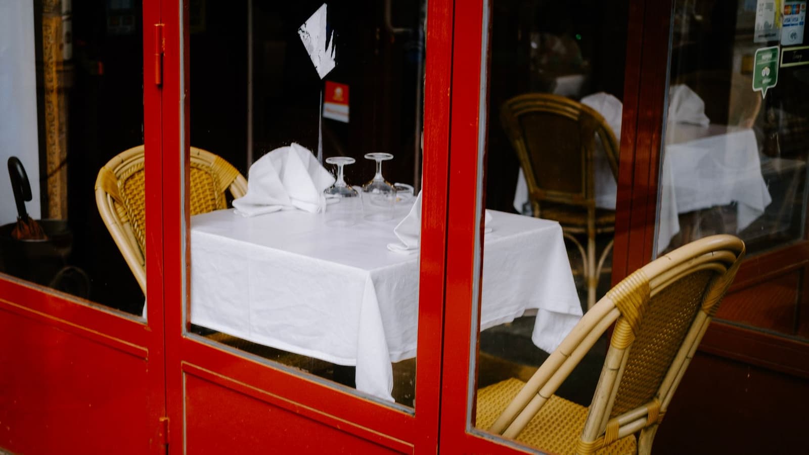 Red-framed Parisian bistro terrace with wicker chairs and set tables