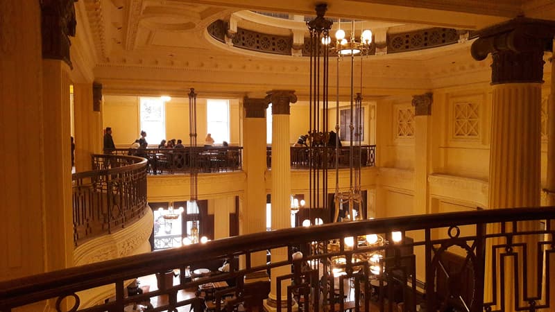 Café de dos plantas con columnas y lámparas en la estación Retiro, Buenos Aires