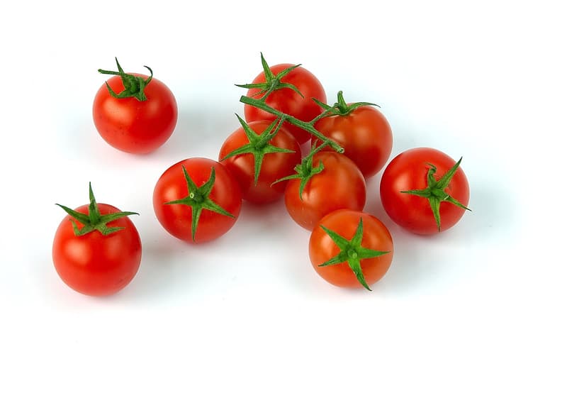 Nine red cherry tomatoes with green stalks lying on a white background