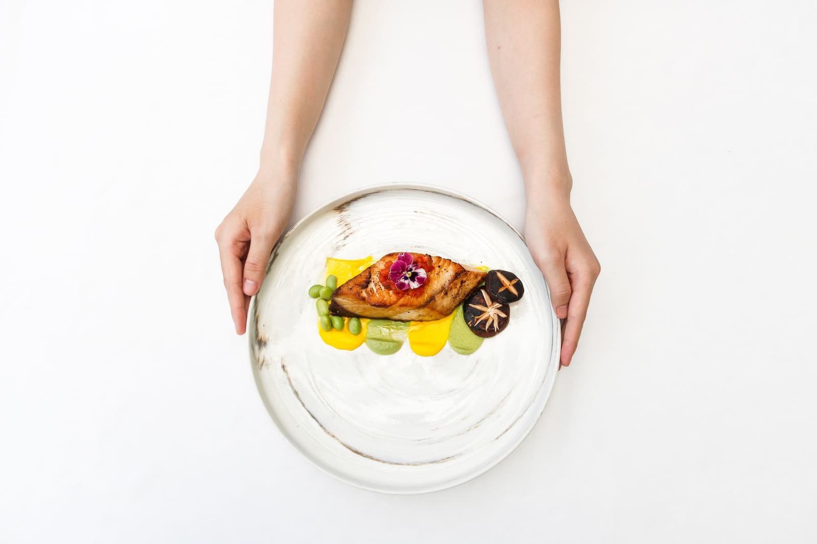 Plato de alta cocina con pescado, setas y una flor comestible