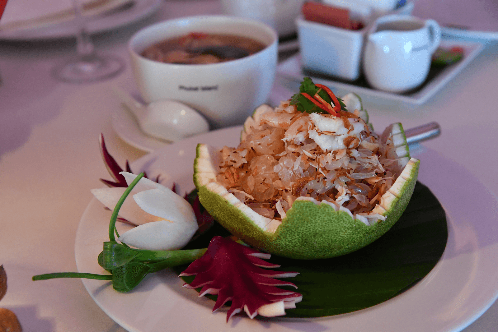 Ensalada de pomelo tailandesa con gambas, cangrejo y coco tostado en un plato blanco