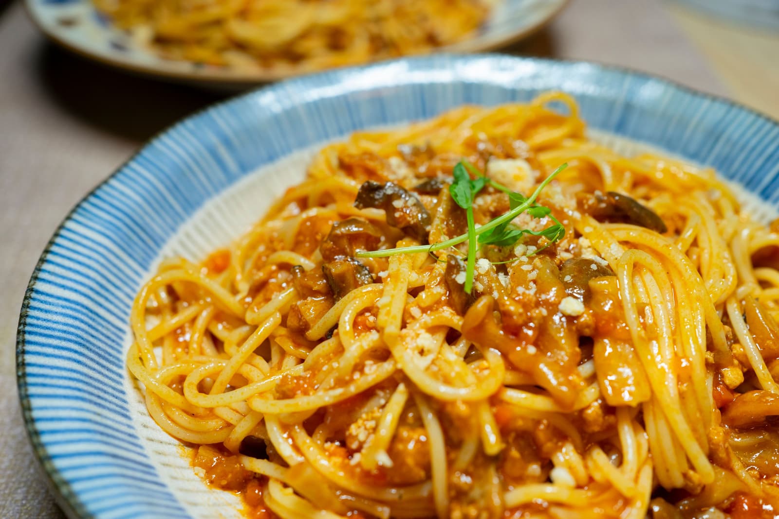 Close-up van een kom spaghetti in tomatensaus met kruiden en geraspte kaas