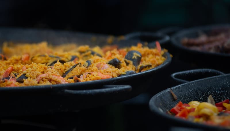 Gros plan de paella de fruits de mer traditionnelle cuisant dans de larges poêles plates