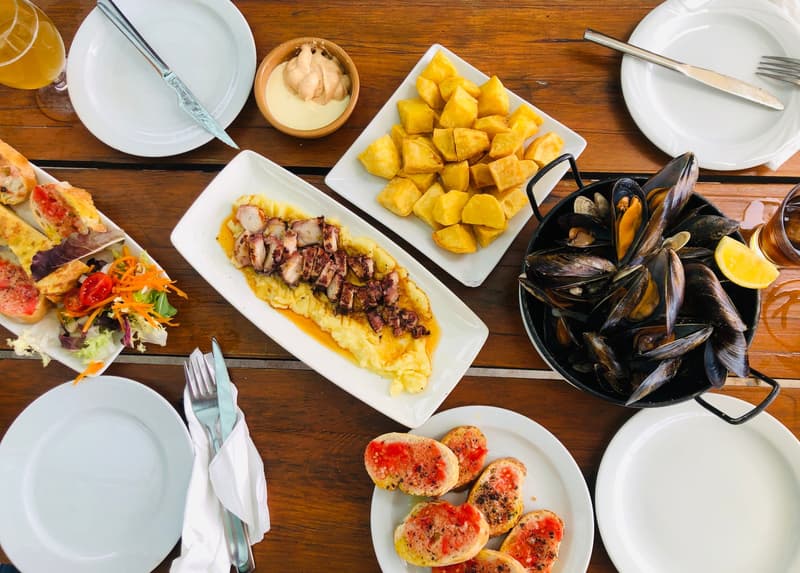 Tisch mit Barcelona-Tapas: Patatas bravas, Pa amb tomàquet, Miesmuscheln und gegrillter Oktopus