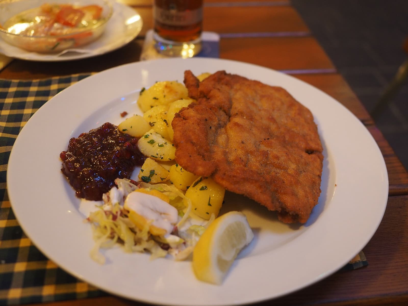 Wiener Schnitzel con patatas al perejil, mermelada de arándanos rojos, ensalada de col y limón